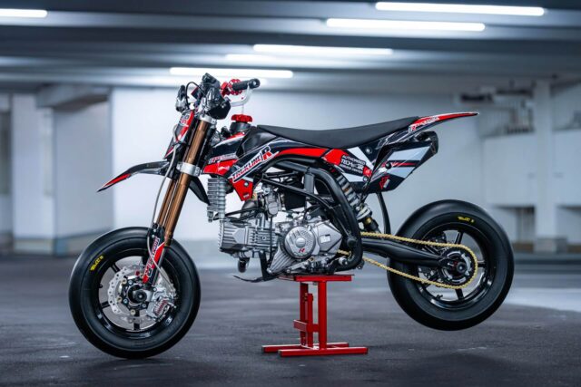 Trckline R 190ccm Pitbike Seitenansicht auf Montageständer, rot-schwarzes Design mit goldenen Felgen